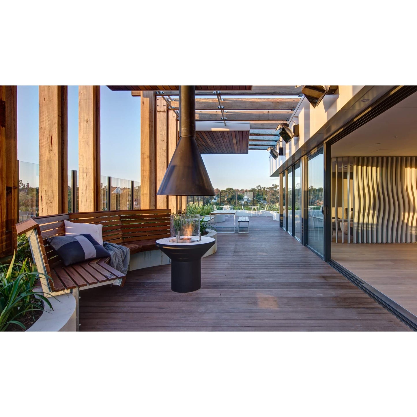 Modern outdoor patio with wooden deck, seating area, and glass walls.