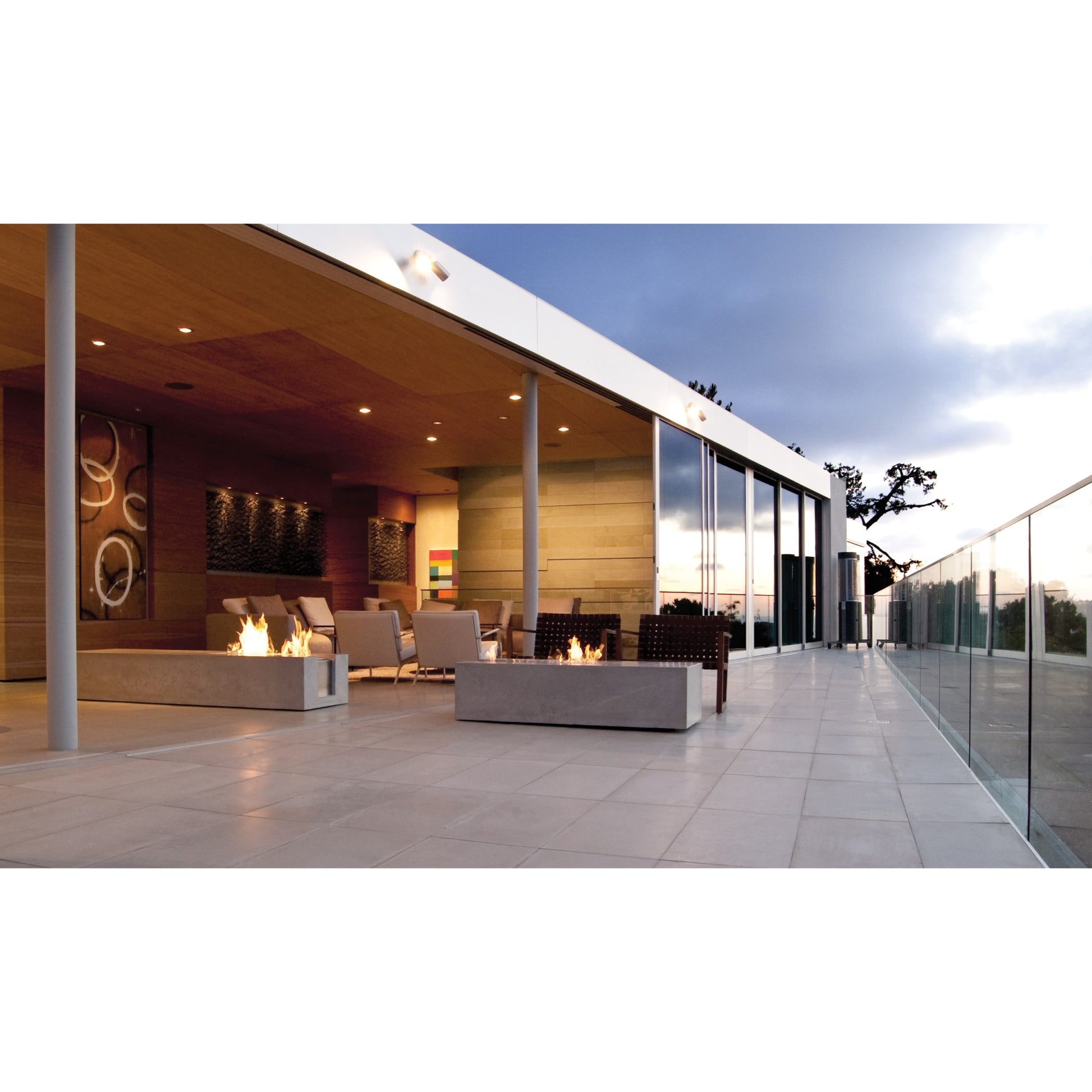 Modern outdoor patio with fire pits and seating area at dusk.