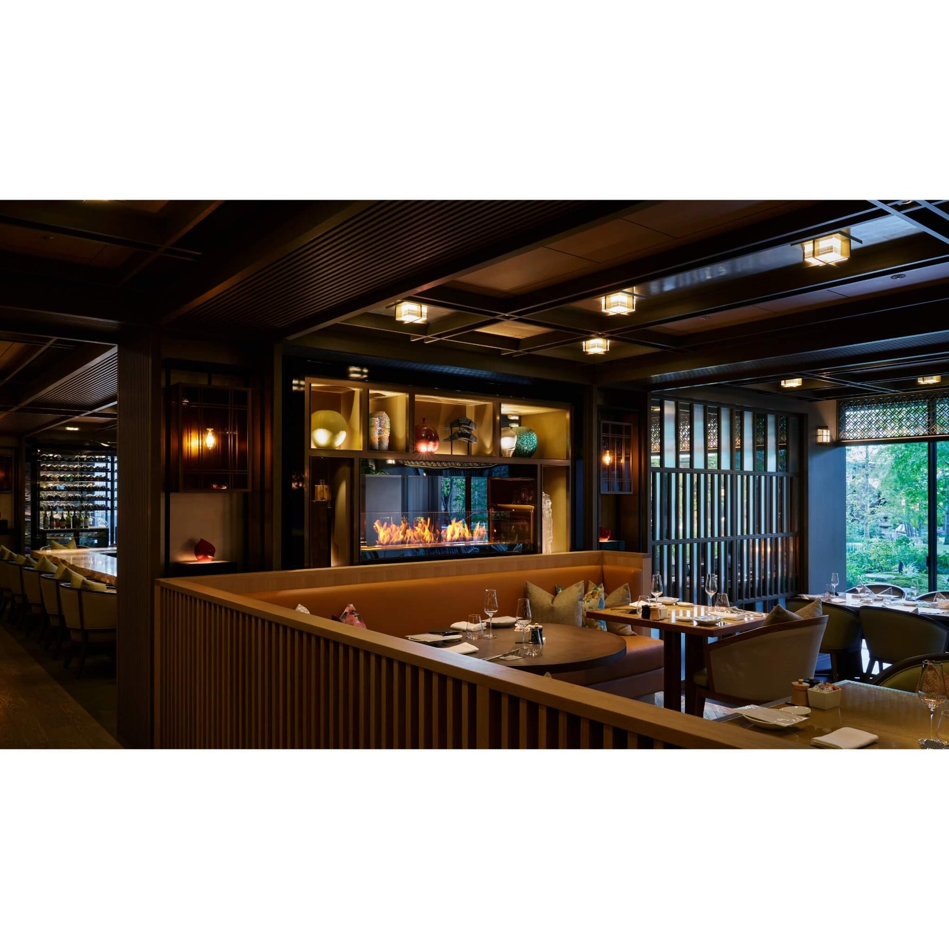 Modern restaurant interior with wooden decor, tables, and a fireplace.