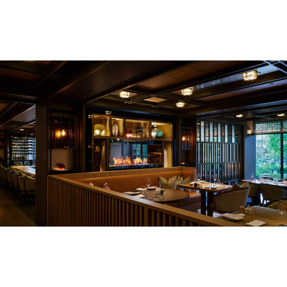 Modern restaurant interior with wooden decor, tables, and a fireplace.