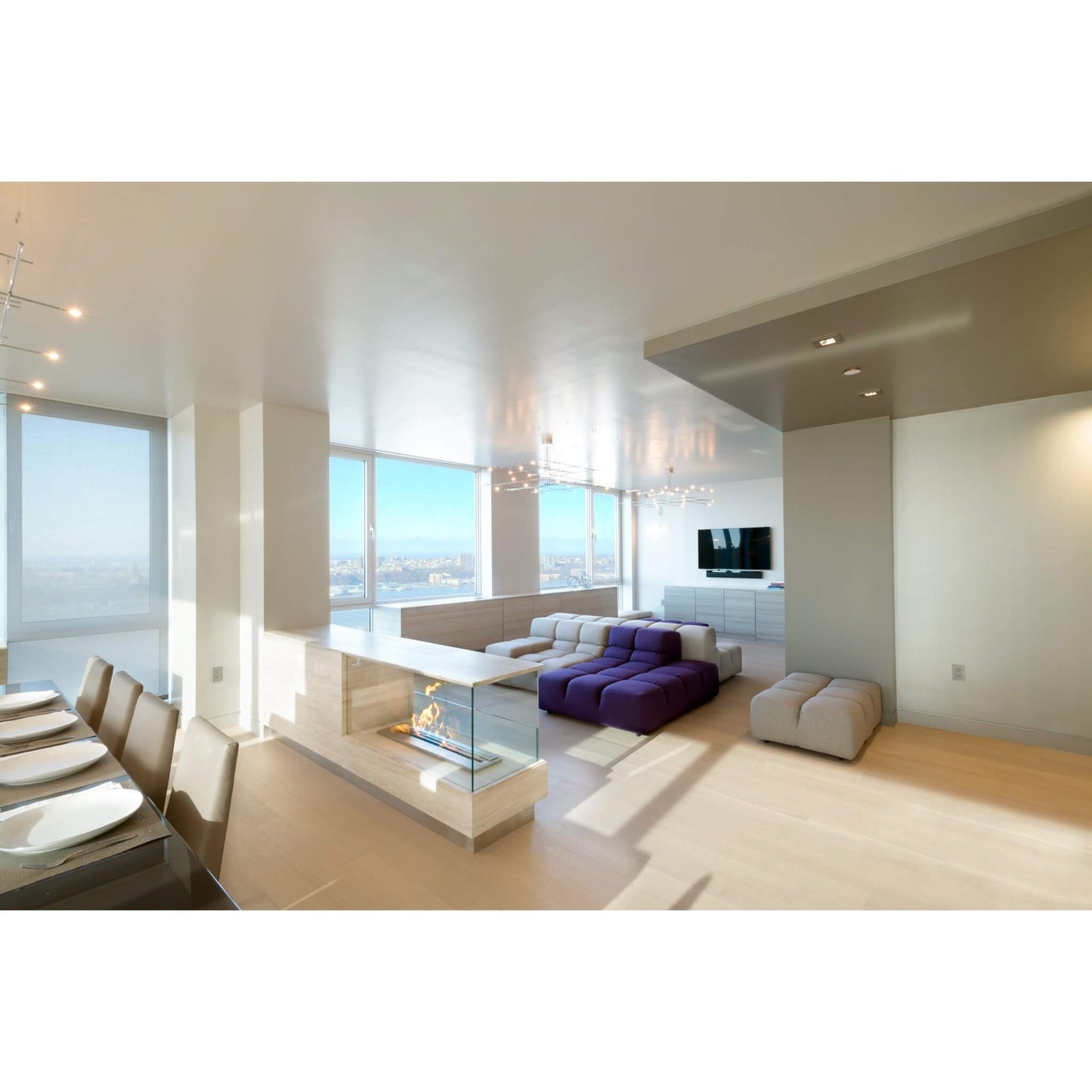 Modern living room with a fireplace, purple sofa, and large windows.