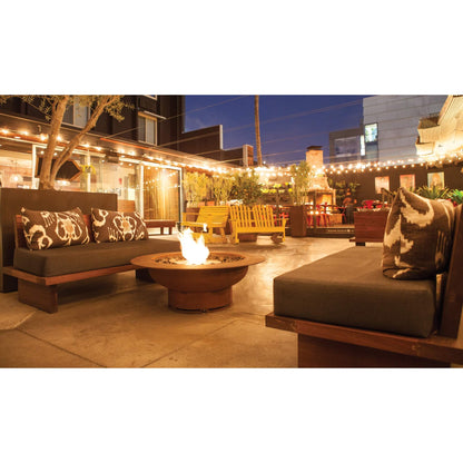 Outdoor patio with fire pit, seating area, and string lights at night.