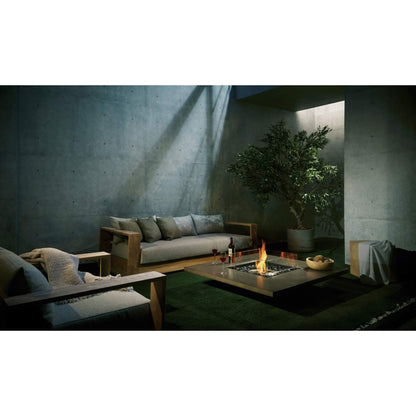 Modern outdoor living space with a fire pit, couch, and potted plant.